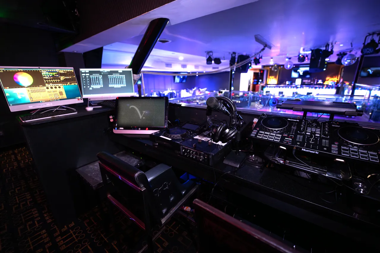 Venue 412 DJ booth with Pioneer CDJs and a Numark controller, dual lighting and audio monitors, and a clear sightline across the main floor.