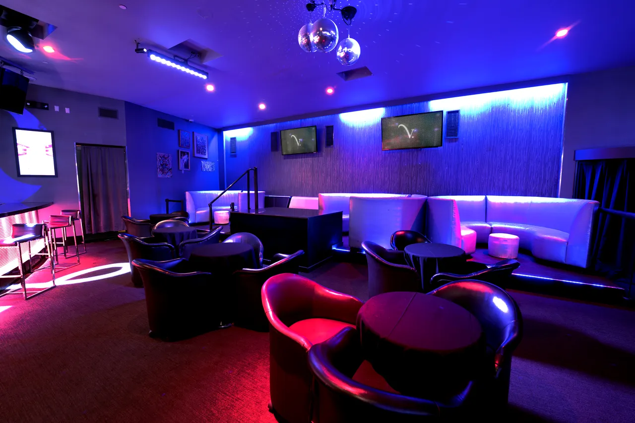 Venue 412 lounge area with overhead disco balls, white and black banquette seating, and ambient red and blue lighting for evening service.