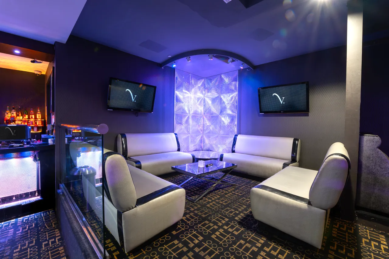 Venue 412 lobby lounge area with white banquette seating, a glass-paneled partition, and TVs displaying the venue logo above.