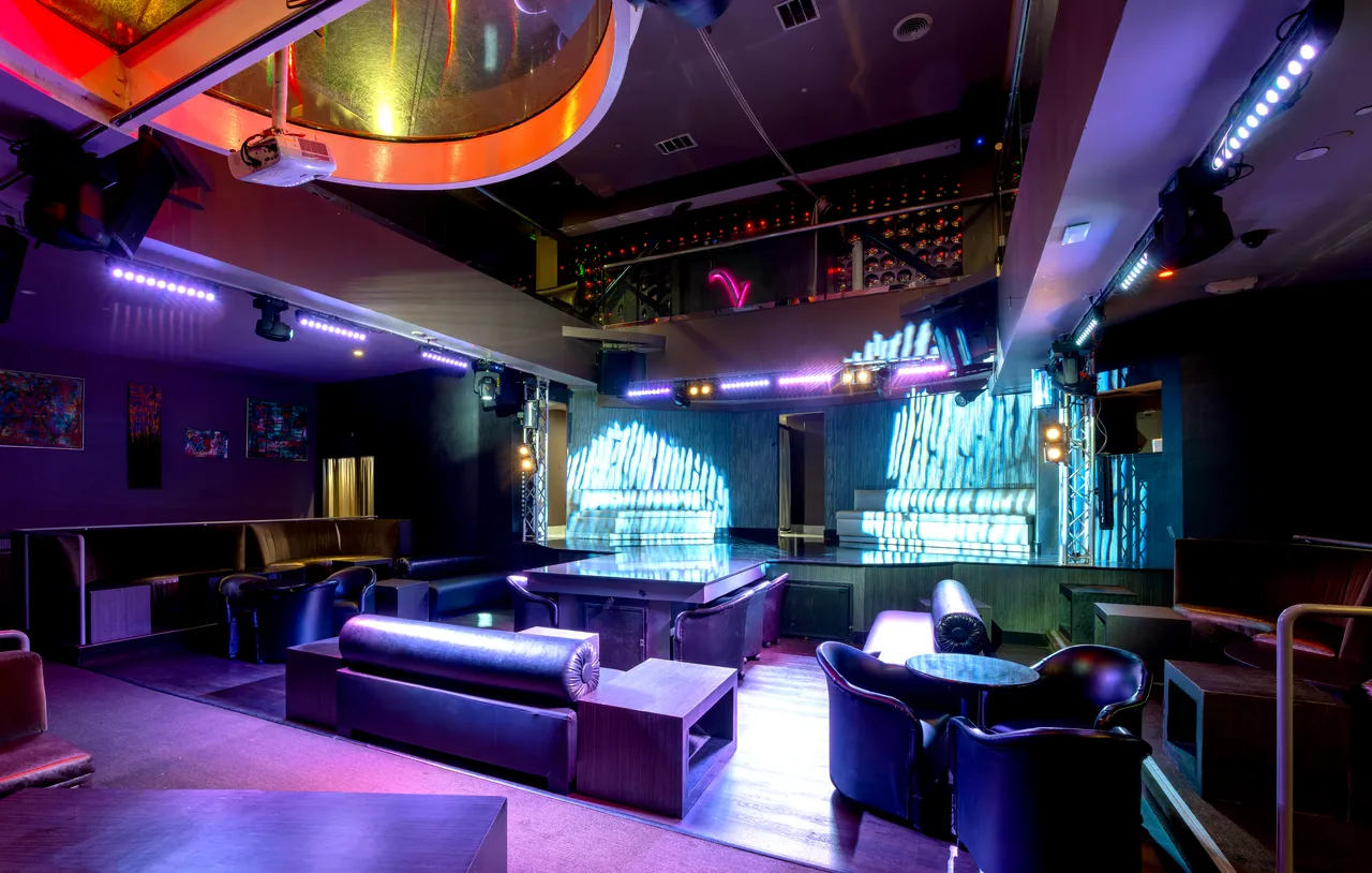 Venue 412 main room with leather bottle service banquettes, lounge tables, and the gradient LED panel walls behind the dance floor.