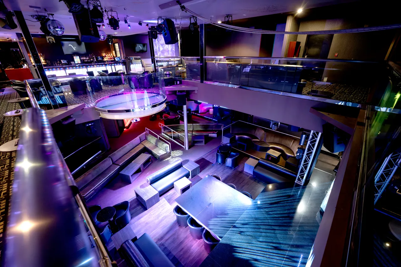 Wide elevated view of the Venue 412 main room from the mezzanine, showing the bar at the back, the dance floor, and the lounge seating throughout.