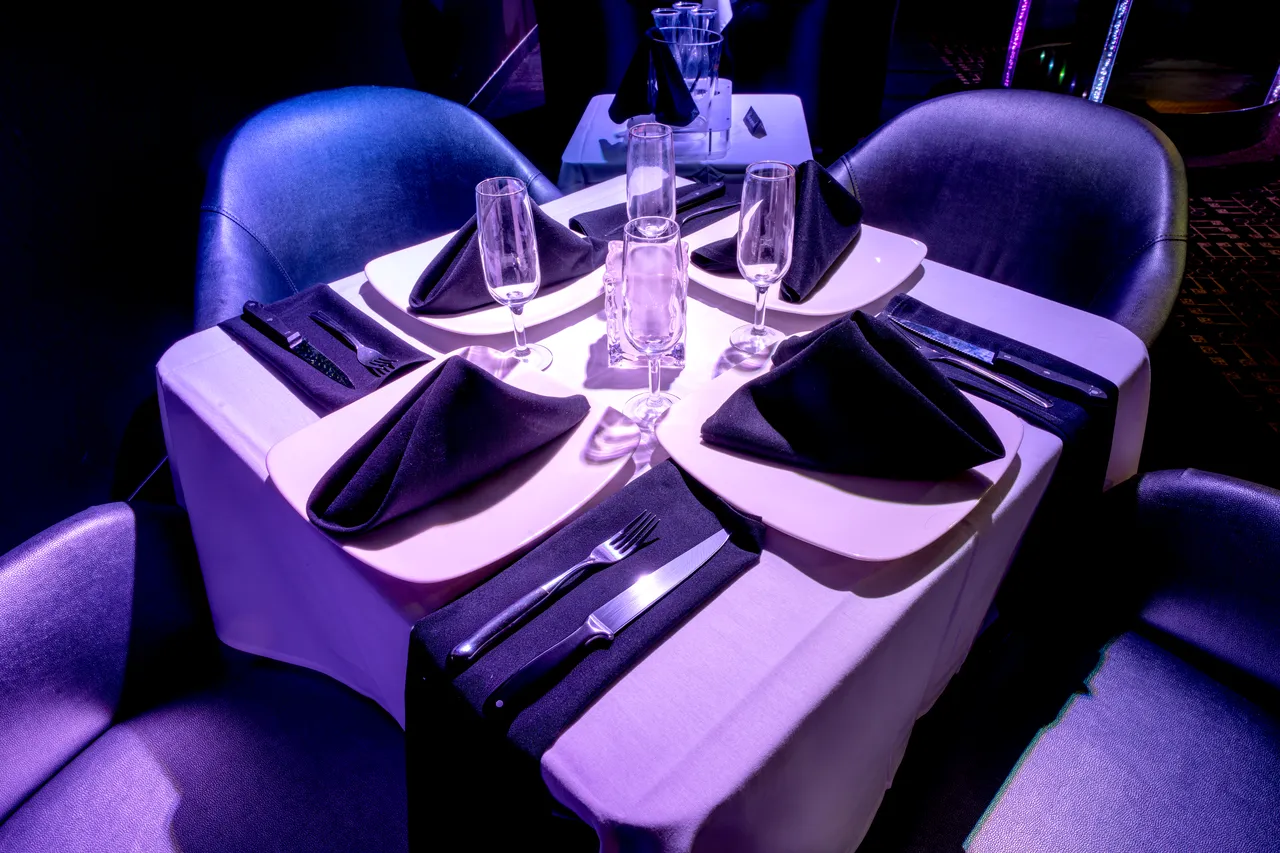 Close-up of a Venue 412 mezzanine dining table with black napkins, white plates, and champagne flutes set for service.