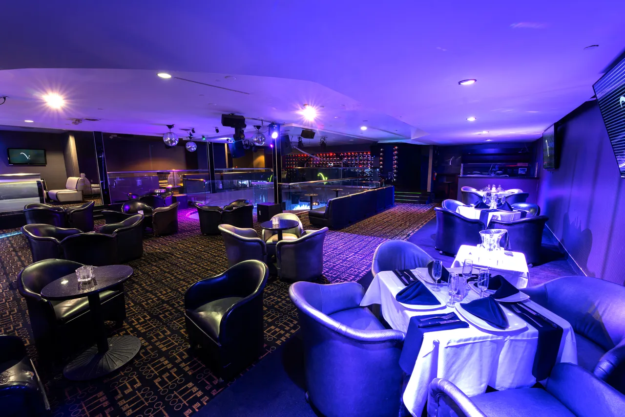 Venue 412 mezzanine level set for dinner — round dining tables with white linens, leather lounge chairs, and the curved railing overlooking the main floor.
